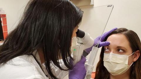 Ophthalmologist examines a patient with a portable slit lamp with a protective shield installed.