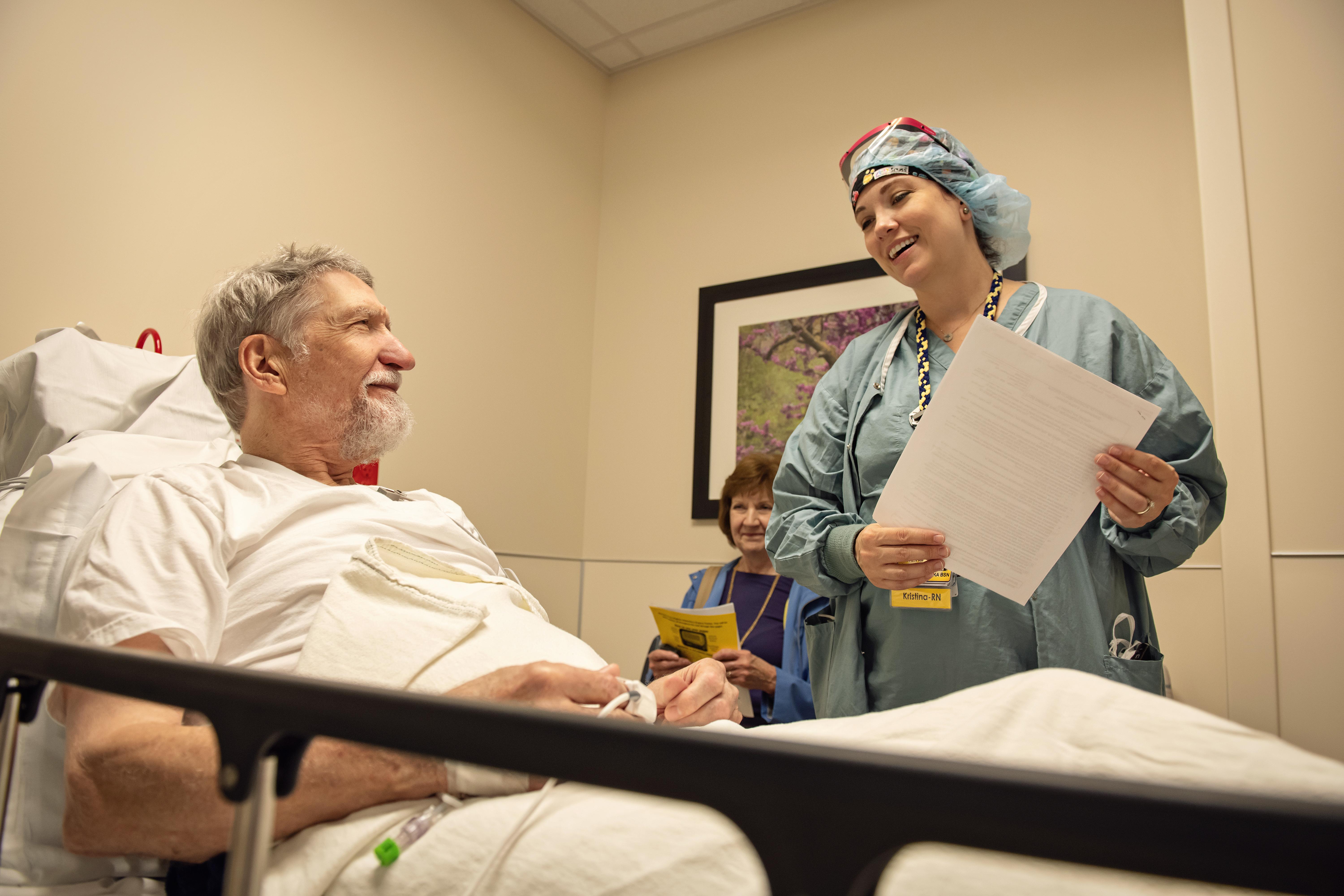 Man laying on hospital bed talking to nurse